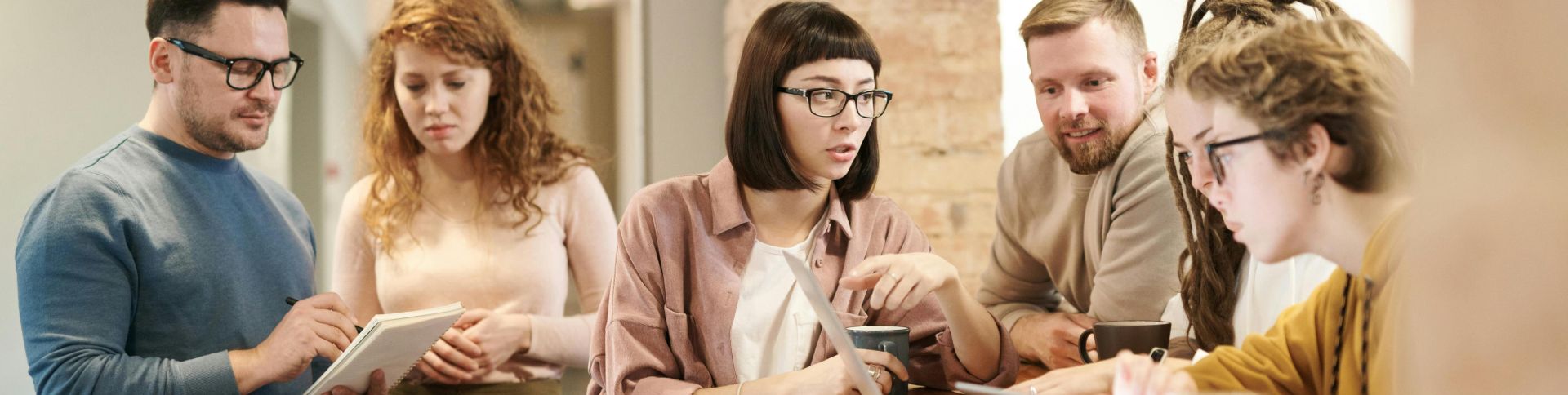A diverse group of coworkers in a modern office engaged in teamwork using technology.